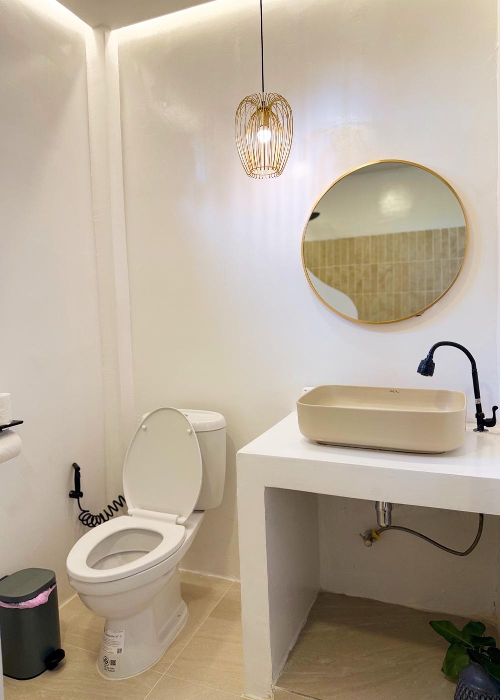 Bathroom with round gold mirror and pendant light
