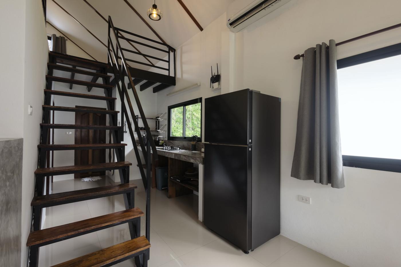 Stairs to the gallery beside the kitchen and full-size fridge